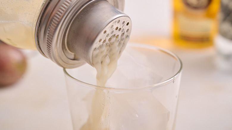 straining margarita into glass