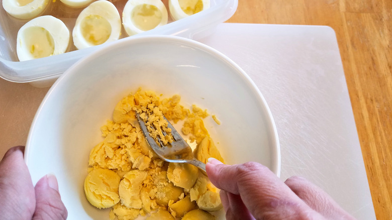 crushing egg yolks with the back of a fork