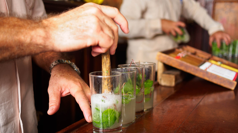 Bartender's hand muddling mojitos