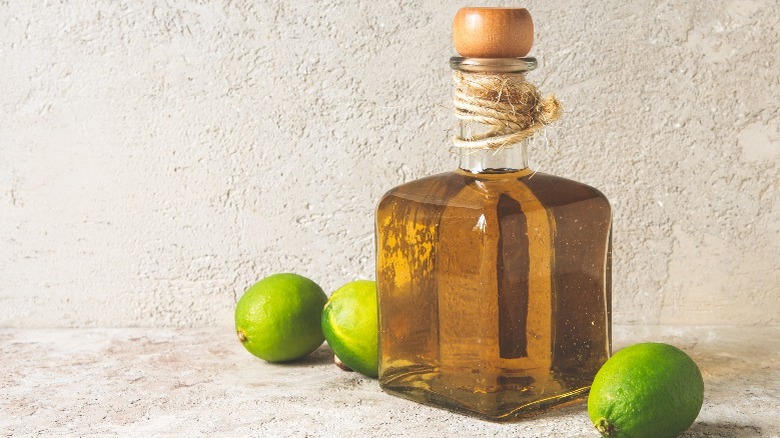 A bottle of gold tequila next to limes