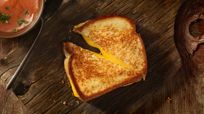 a cut grilled cheese melting on a wooden board