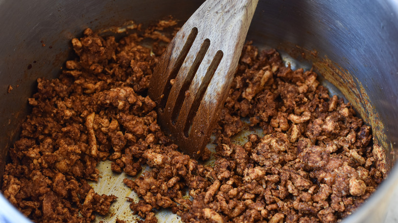 browning ground turkey in pot with wooden spatula