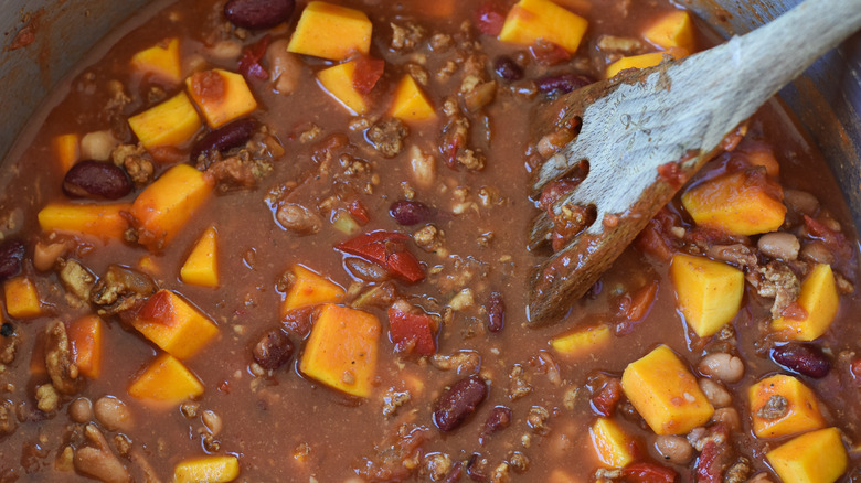 chili simmering in pot with wooden spatula