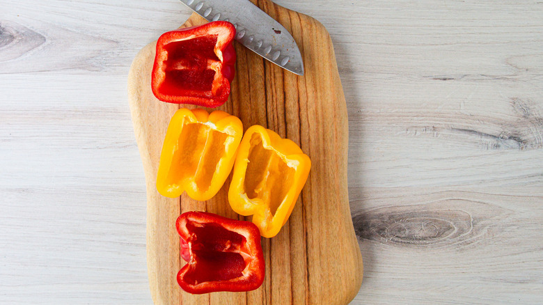 Bell pepper halves on cutting board with knife