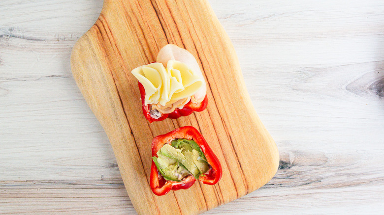 Bell pepper halves with filling on cutting board