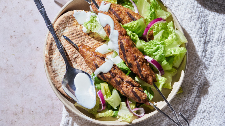 kebabs, pita, lettuce on plate