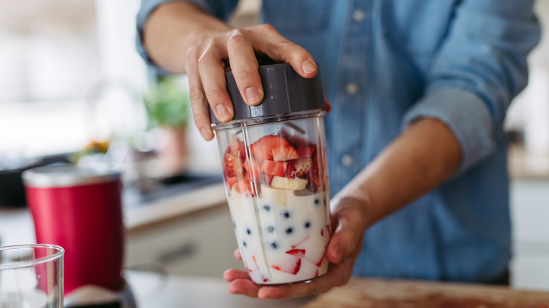 close up of hands blending a fruit smoothie