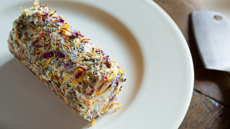 Flower-covered goat cheese log on plate