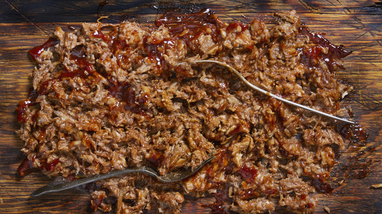 Shredded pulled pork on a wood board