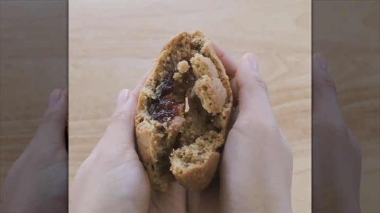 hands pulling apart a peanut butter and jelly stuffed cookie