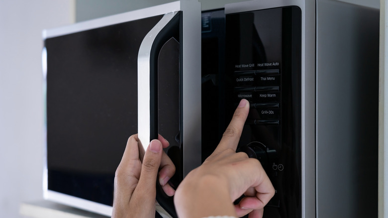 Woman pressing buttons on microwave