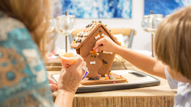 Child and adult creating Halloween gingerbread house