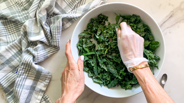 hand in bowl massaging kale