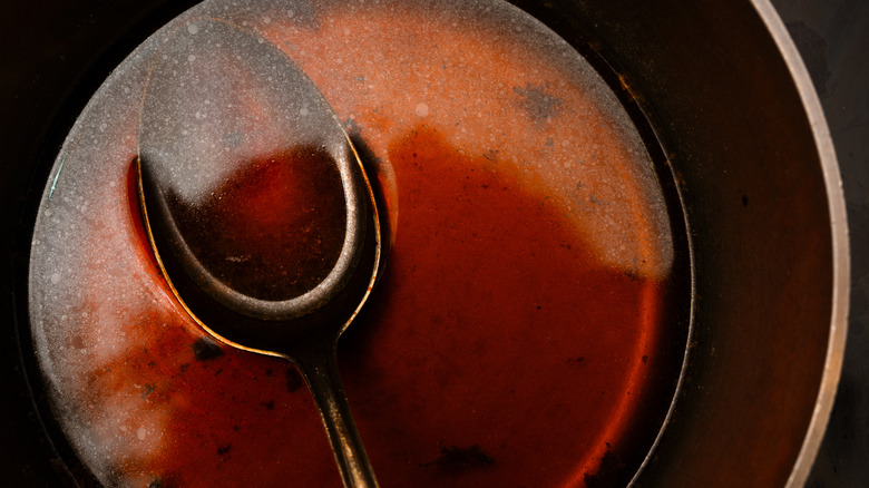 spoon in skillet of brown demi-glace