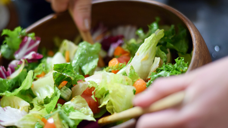 Tossing salad in wooden bowl