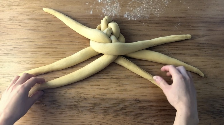 hands braiding challah dough