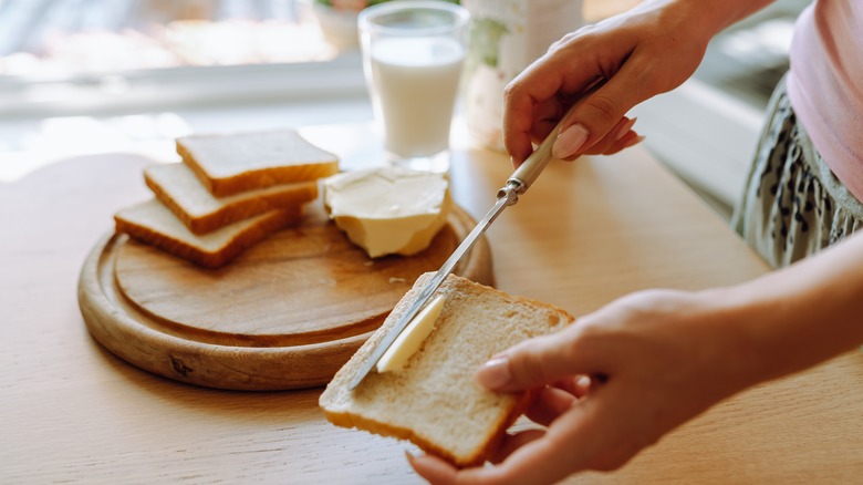 Spreading butter on slice of bread