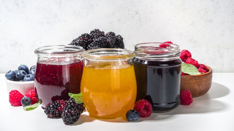 Jars of fruit jam and fresh berries