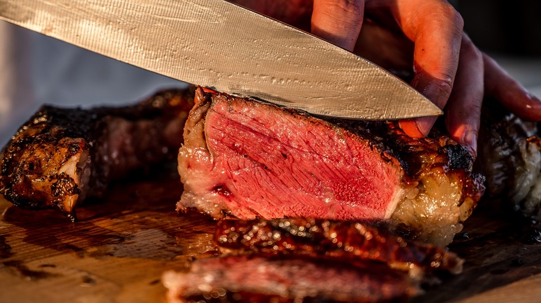 Slicing into a rare tomahawk steak