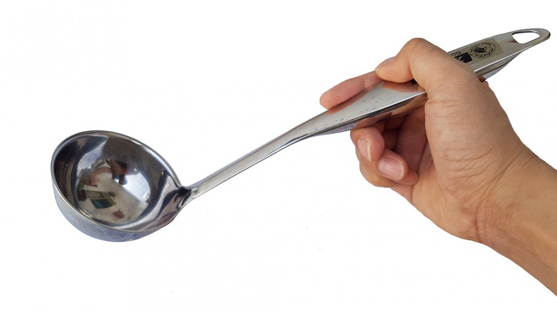 Hand holding stainless steel ladle