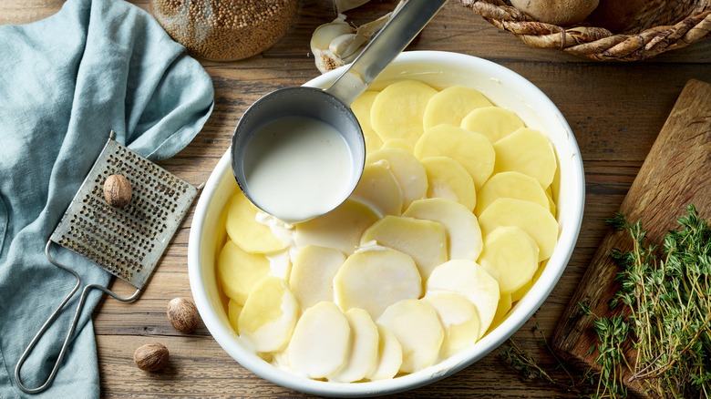 Cream being poured into a potato gratin pan