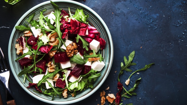 Top-down view of beets, arugula, walnuts, and cheese on plate