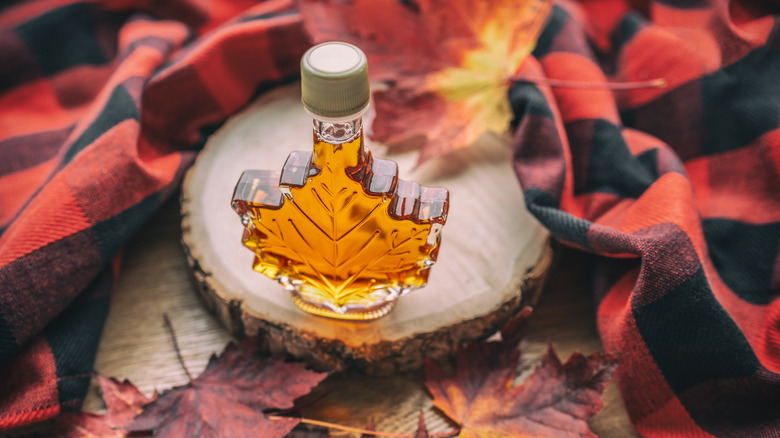 Maple syrup surrounded by flannel and leaves