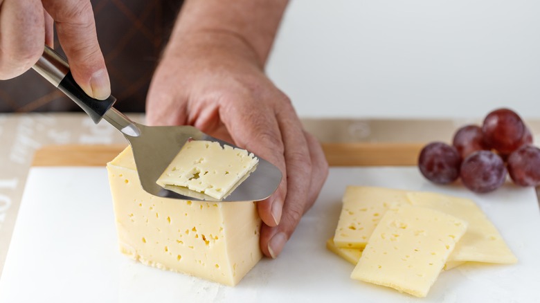 person using cheese slicer