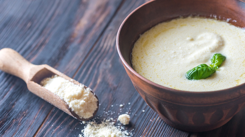 Alfredo sauce beside scooper of parmesan