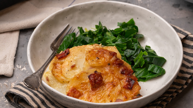 potatoes au gratin in bowl with greens