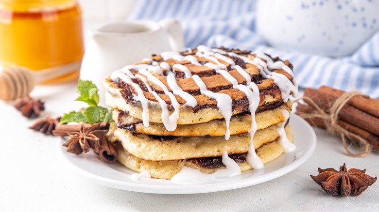 plate of cinnamon roll pancakes drizzled with milk glaze