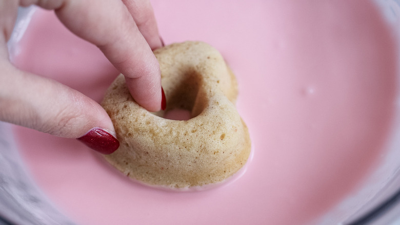 dipping donut in pink glaze