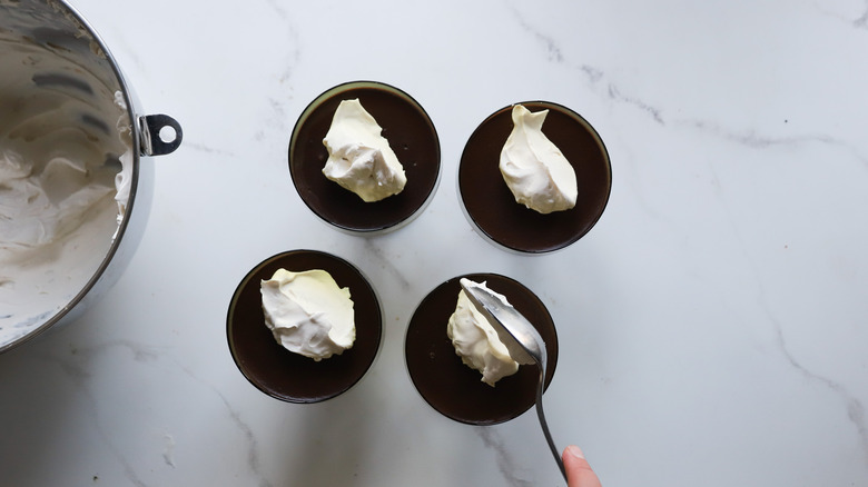 spoon adding whipped cream on pudding