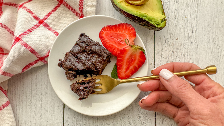 vegan avocado brownie on plate with strawberries and fork