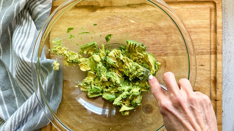 mashing avocados with fork in bowl