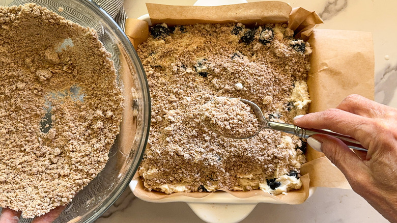 hand adding crumb topping