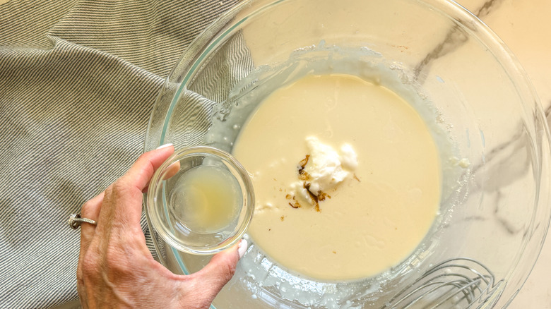 hand adding lemon juice to bowl