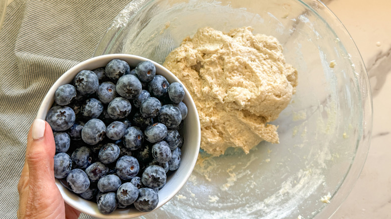 hand adding blueberries to bowl