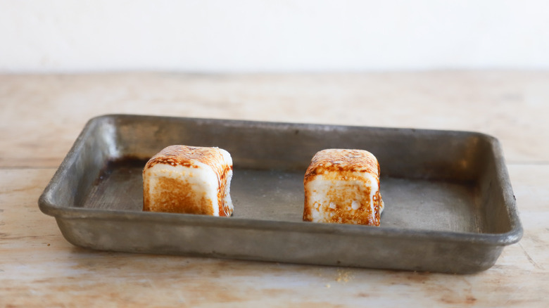 Two toasted marshmallows on pan