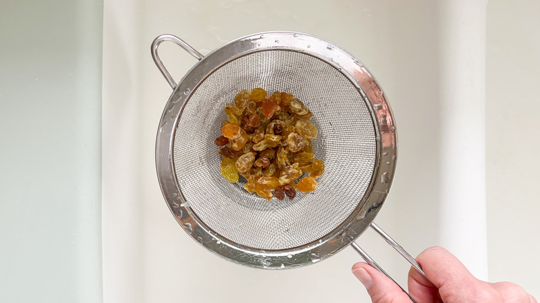 Golden raisins in strainer over sink