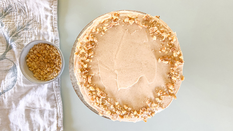 Vegan carrot cake with cinnamon-cashew frosting and chopped walnut garnish