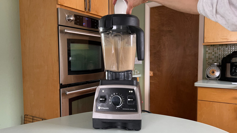 Adding coconut oil to cinnamon-cashew frosting in blender