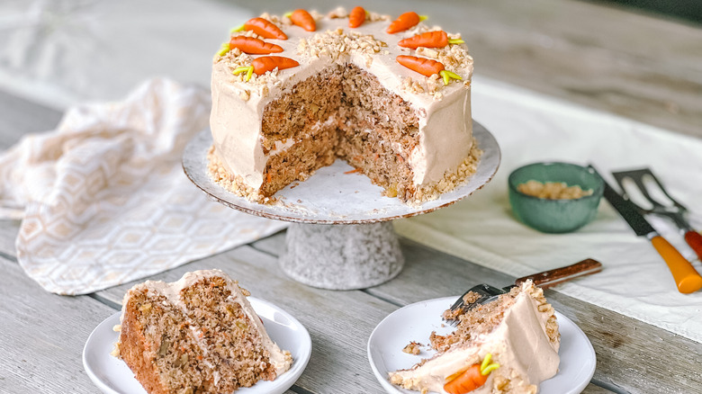 Vegan carrot cake with cinnamon-cashew frosting and marzipan carrots cut with slices on plates