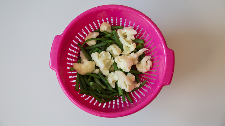 pink colander with drained vegetables