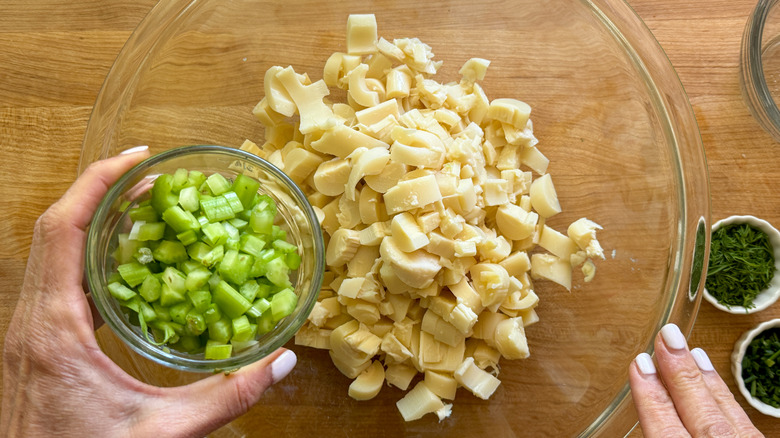 hand adding celery to bowl