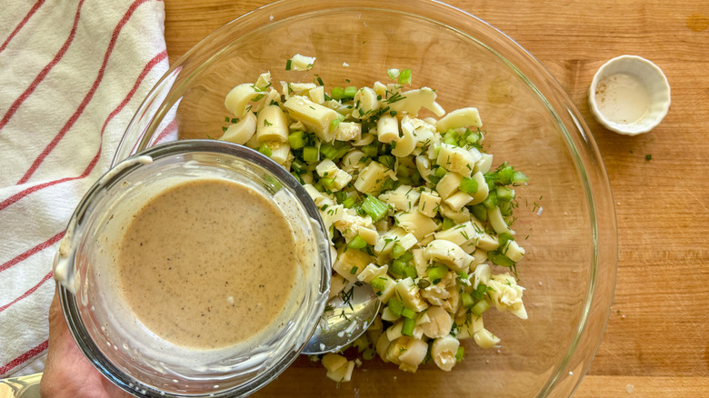 hand adding dressing to bowl