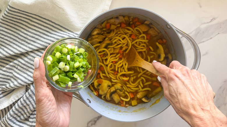 hand adding scallions to dish