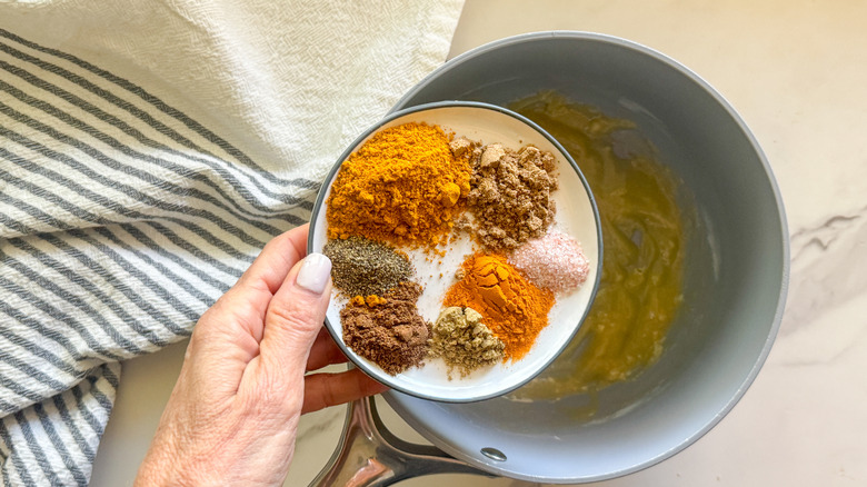 hand adding spices to pot