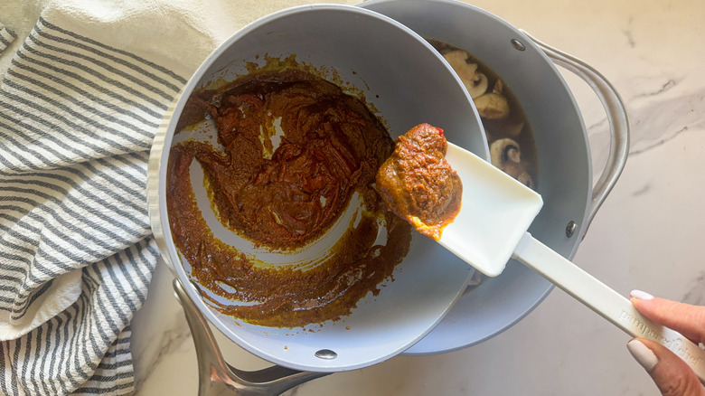 hand adding roux to pot