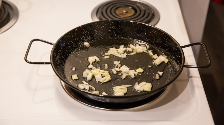 onion sauteing in paella pan 